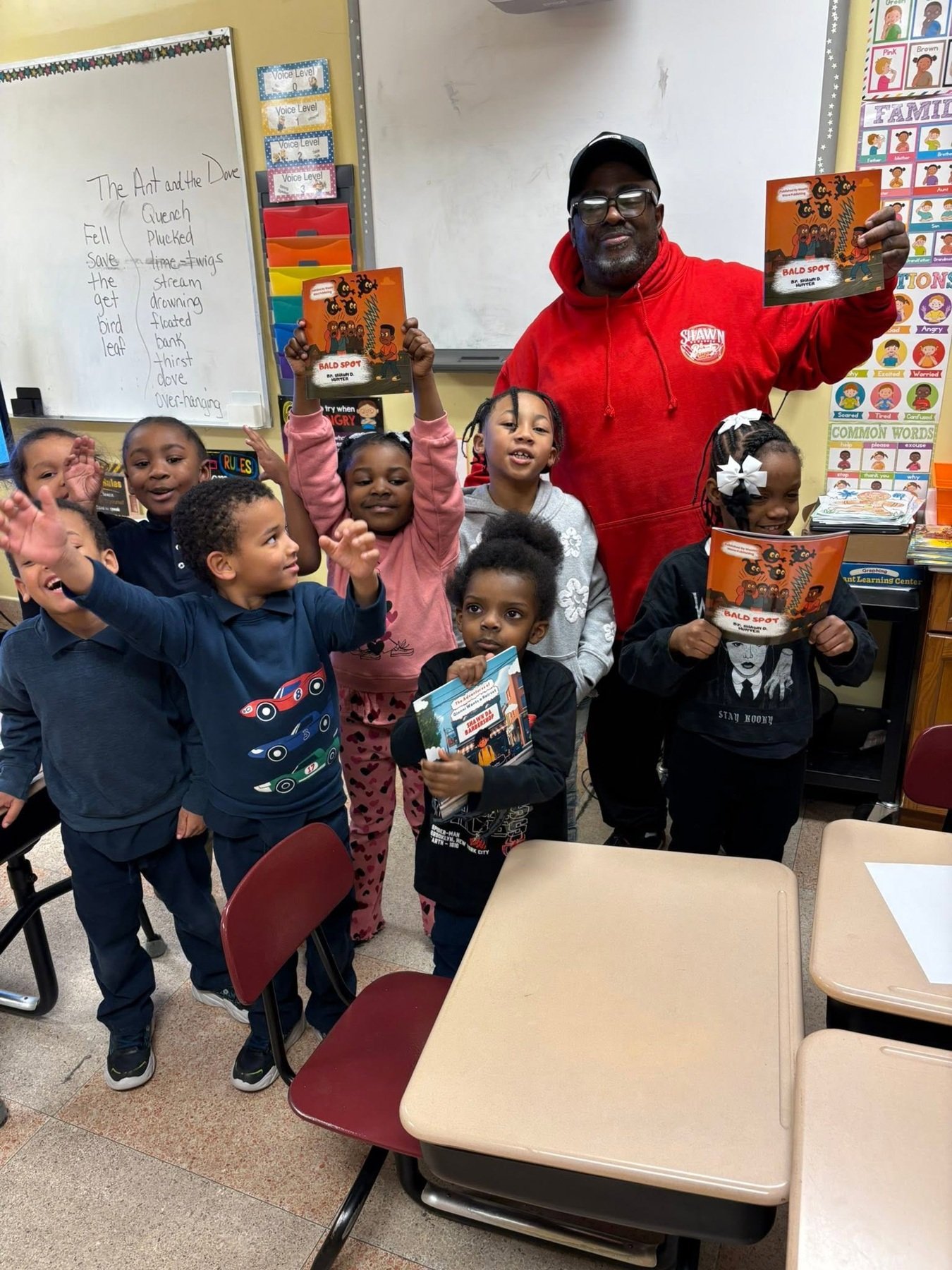 Shawn with young readers holding books in a classroom